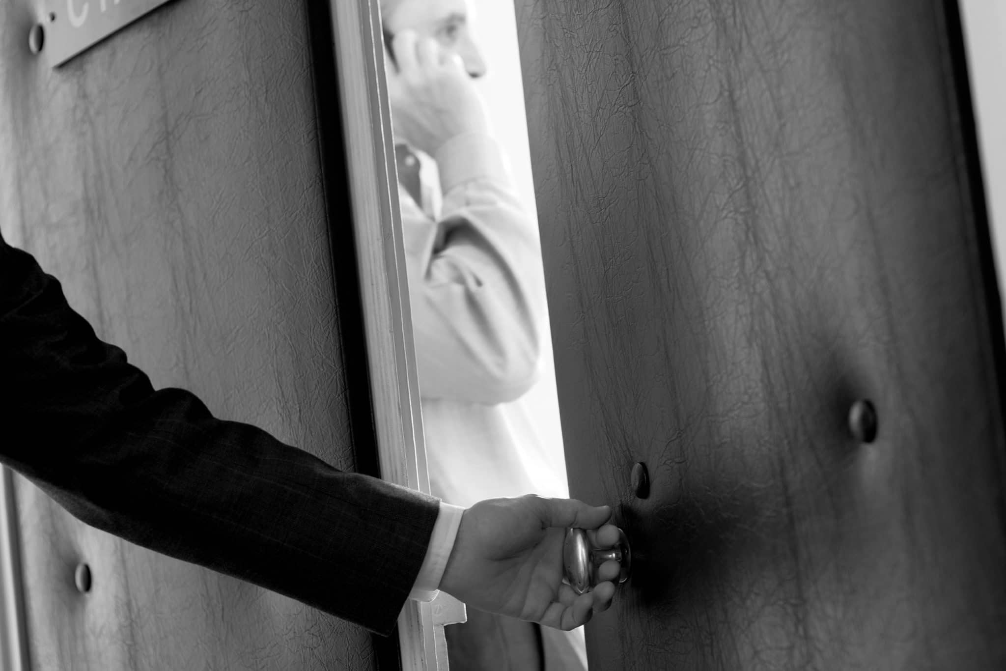 reportage corporate, photo de détail d'une main ouvrant la porte d'une salle de réunion