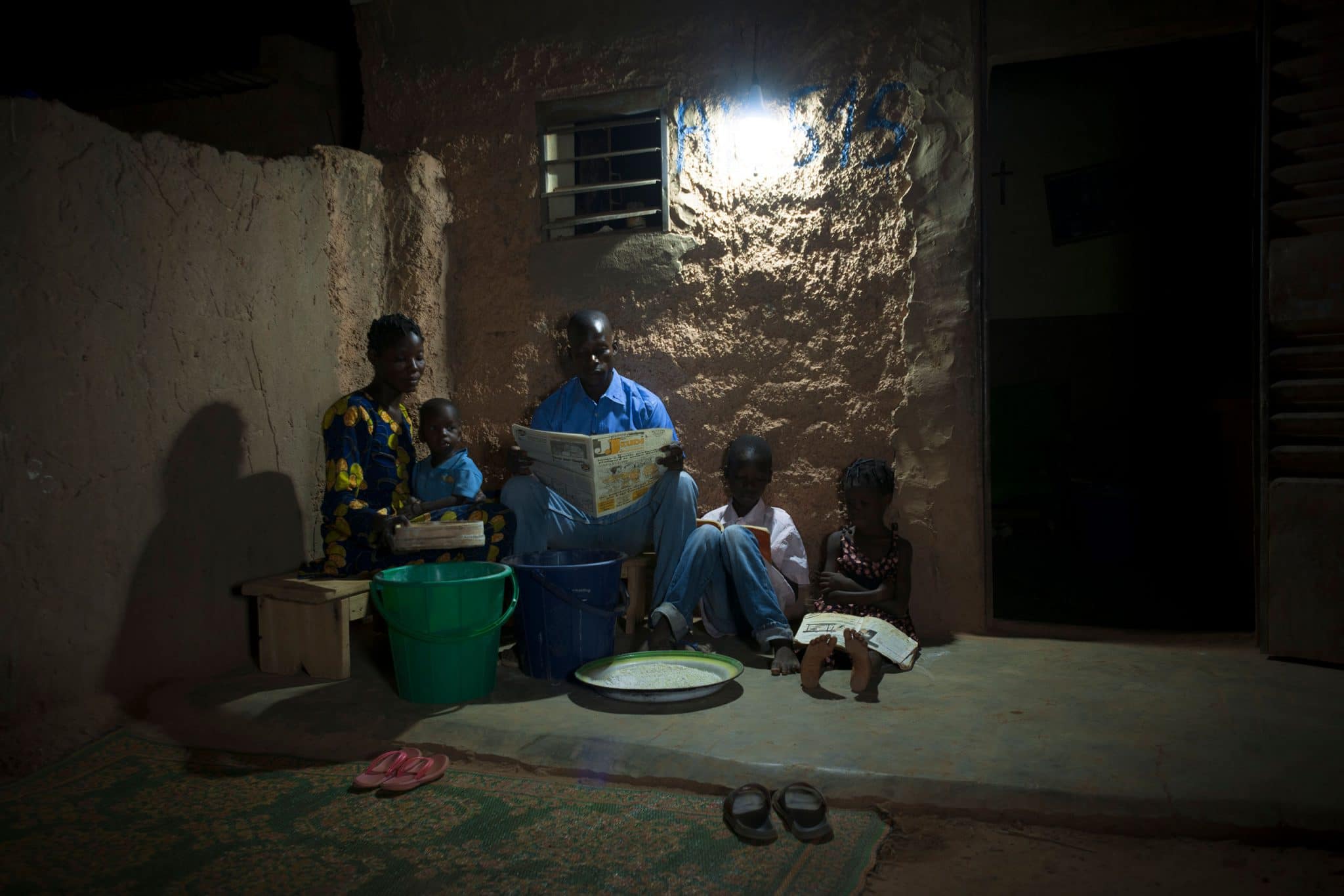Villageois dans les faubourgs de Ouagadougou séclairant avec les lampes solaires Awango by TotalEnergies