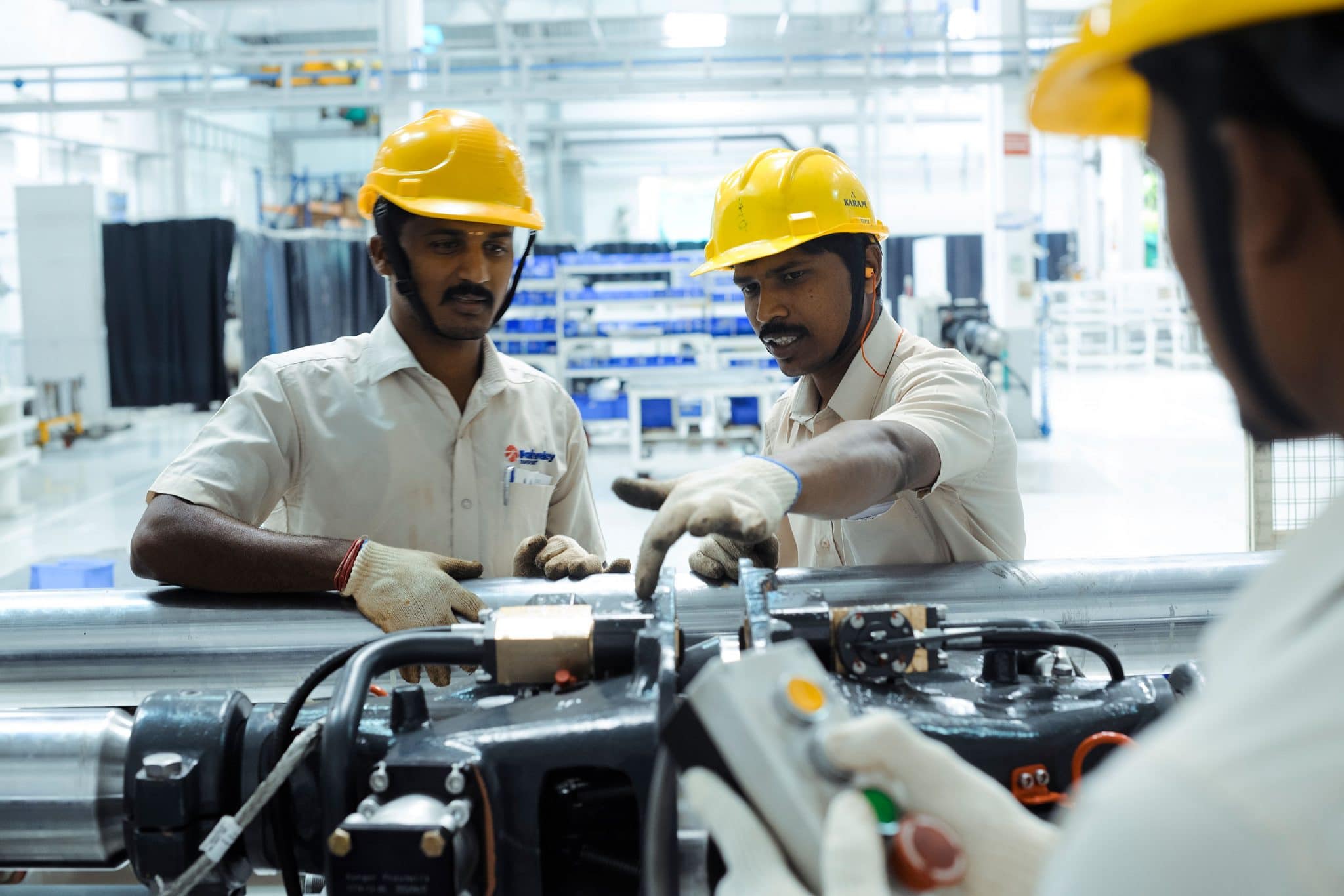 Discussion autour d'un élément de train en cour de fabrication par 3 ouvriers du groupe Wabtec dans l'usine d'Hosur en Inde
