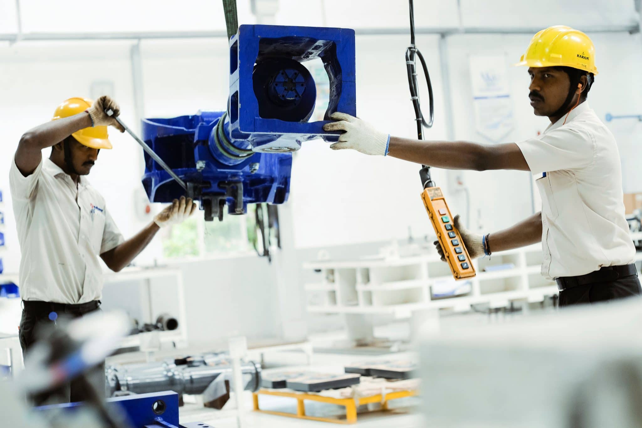 manutention par 2 ouvrier d'une pièce métallique dans l'usine d'Hosur du groupe Wabttec en Inde