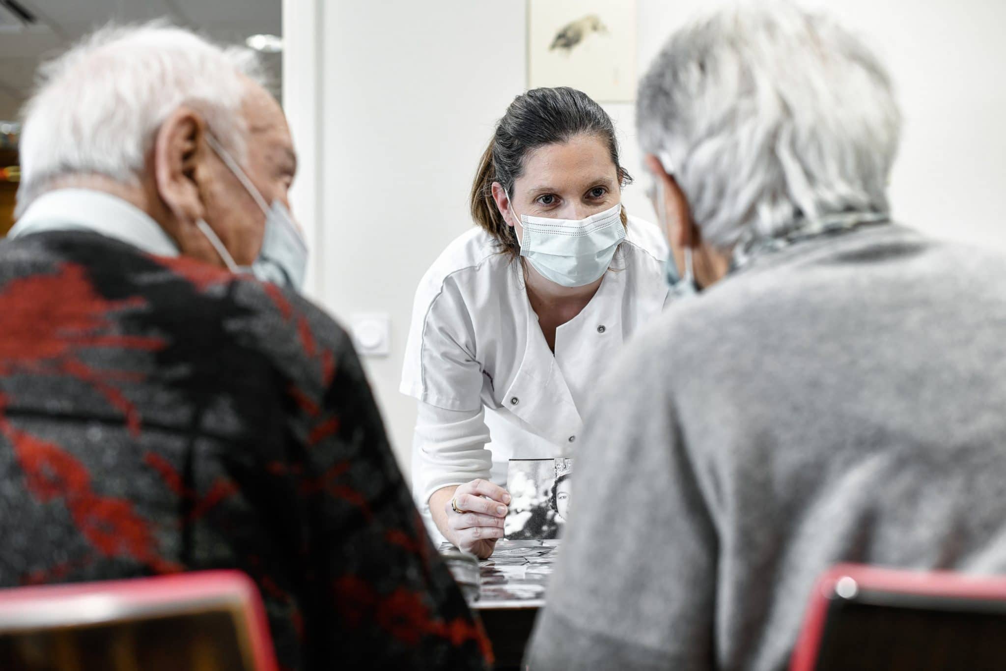 Reportage Santé professionnel en Maison de Retraite à Paris. EHPAD Fondation Aulagnier. Une ergothérapeute jouant avec 2 résidents atteint d'Alzheimer.