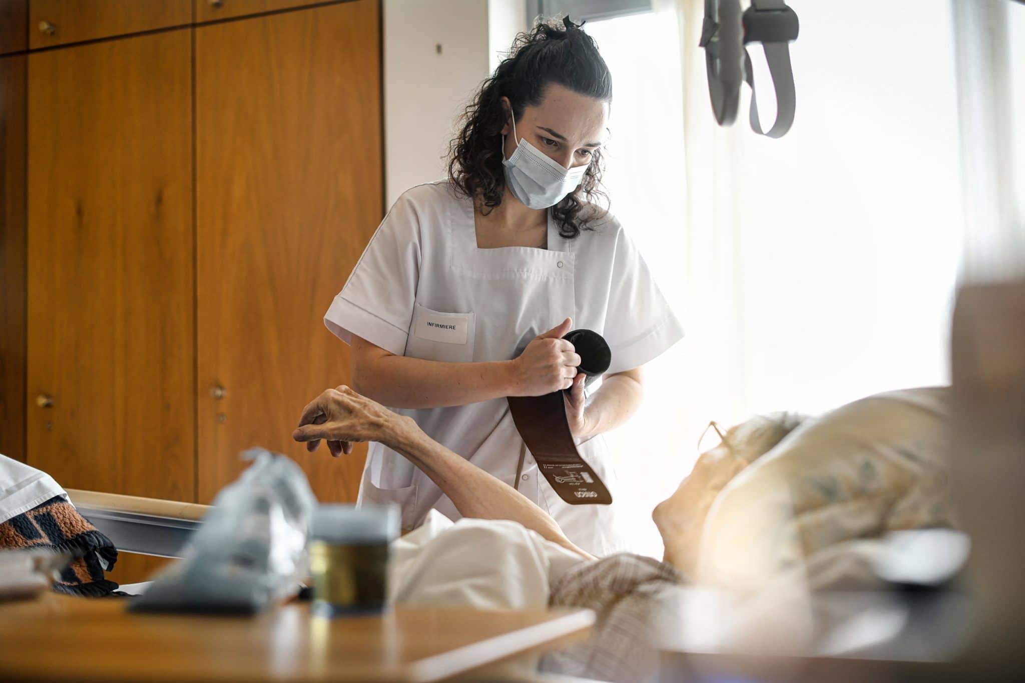 Reportage Santé en Maison de Retraite à Paris. EHPAD Fondation Aulagnier. Une infirmière prend la tension d'un résident.