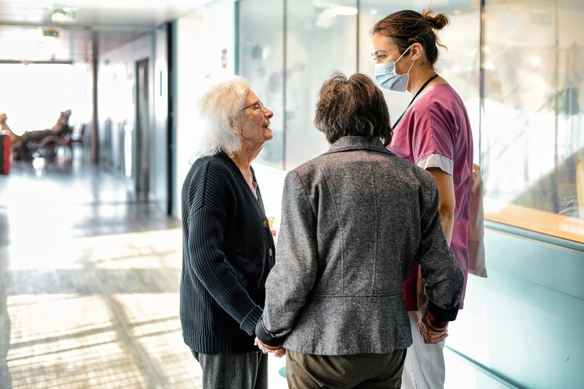 Reportage phot ographe en Ehpad à Paris.EHPAD Lasserre. Aide-sognante en discussion avec 2 résidentes en unité Alzheimer.